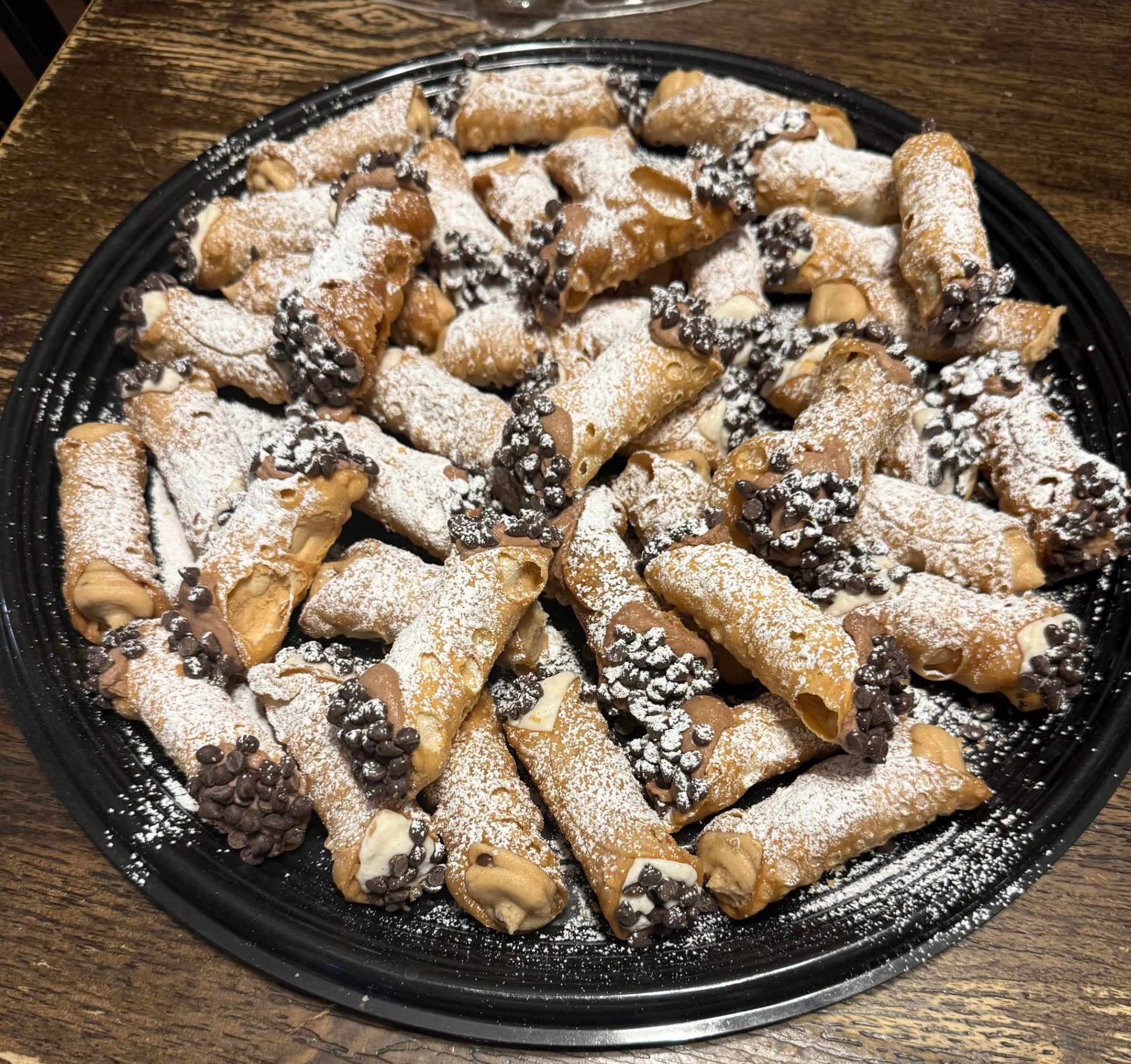 Large cannoli platter with chocolate chip cannoli dusted with powdered sugar